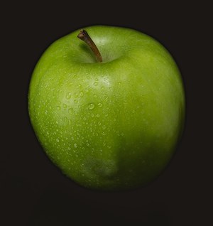 A green apple on a dark cloth